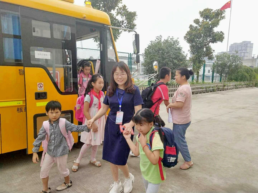 圖為校車照管員阿姨護(hù)送孩子上下學(xué)。