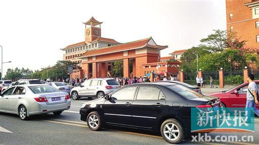 學校門口的路段停滿前來接送孩子的車輛,不少家長在校門口等候。